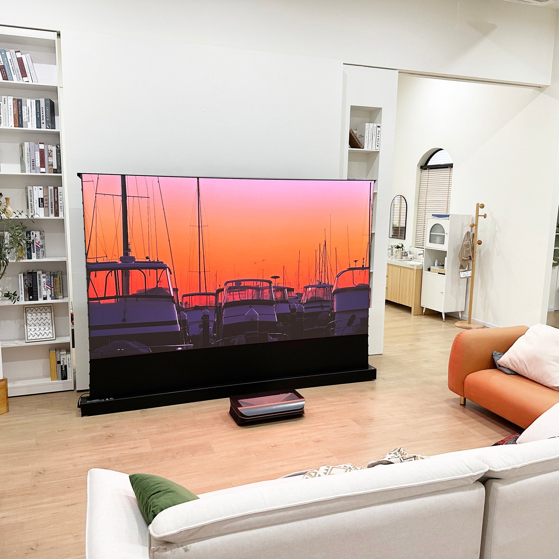 Short throw TV projector and acoustic projector screen displaying vivid sunset scene in modern living room.