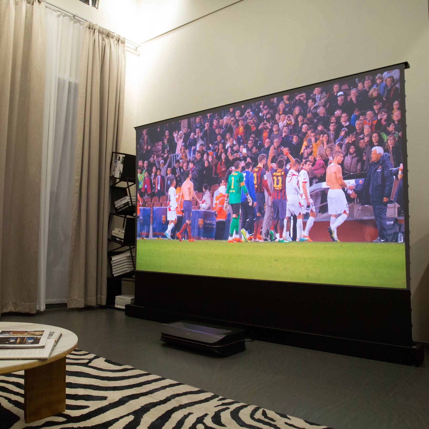 AWOL Vision projector enhances a sports watching experience with a soccer match displayed on a large screen, perfect for gathering with friends.